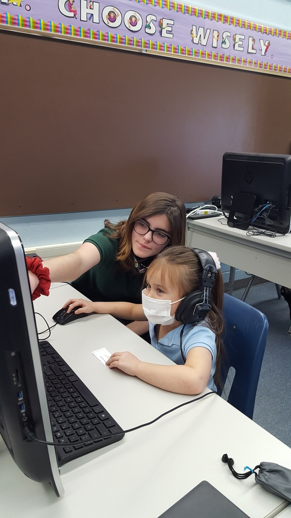 8th graders helping kindergarten buddies on computers